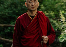 A serene Buddhist monk stands in nature, embodying spirituality and tradition.